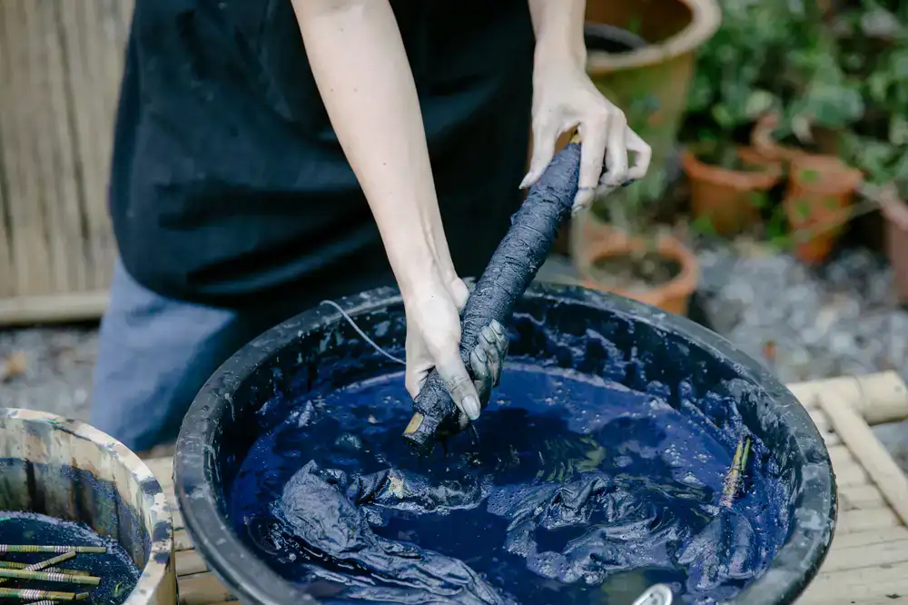 Fabric being lifted from a deep indigo dye vat
